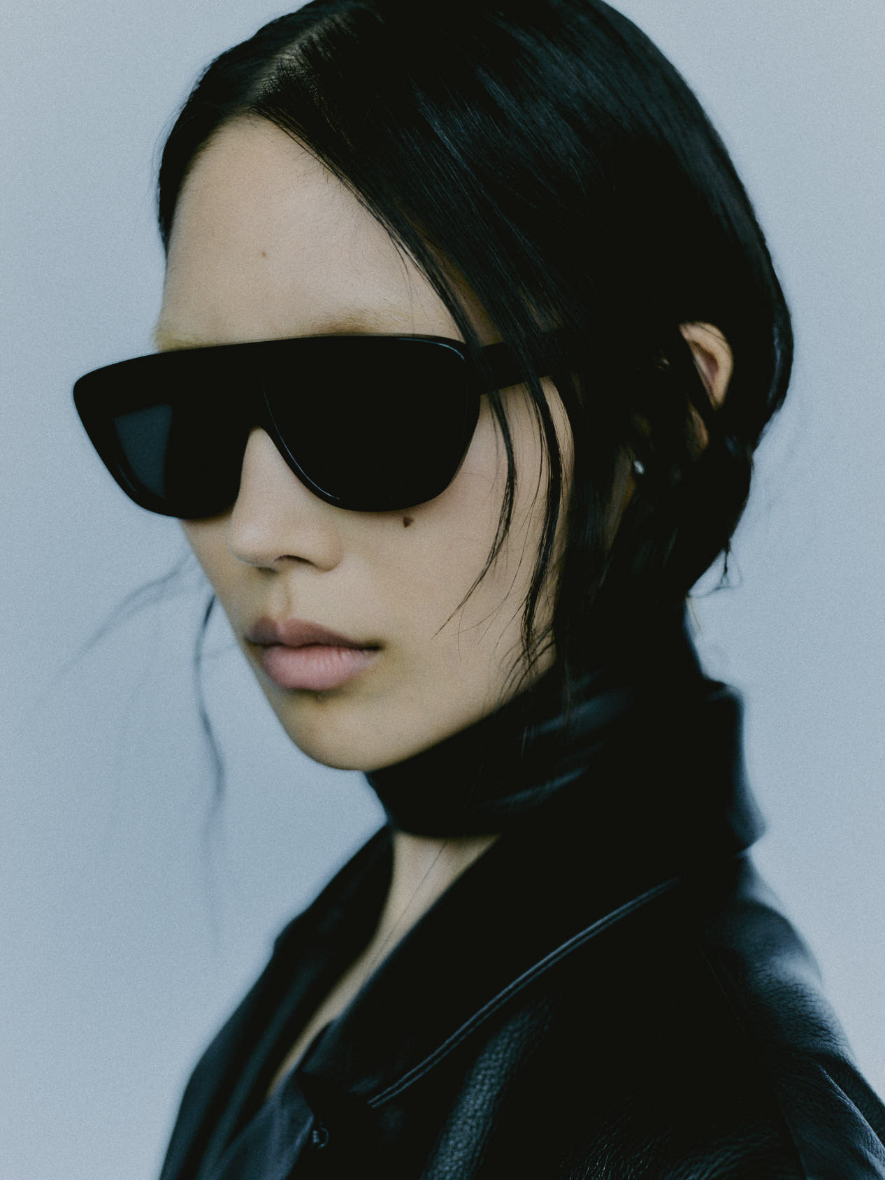 Model wearing 080 black acetate sunglasses with black leather jacket, minimal background